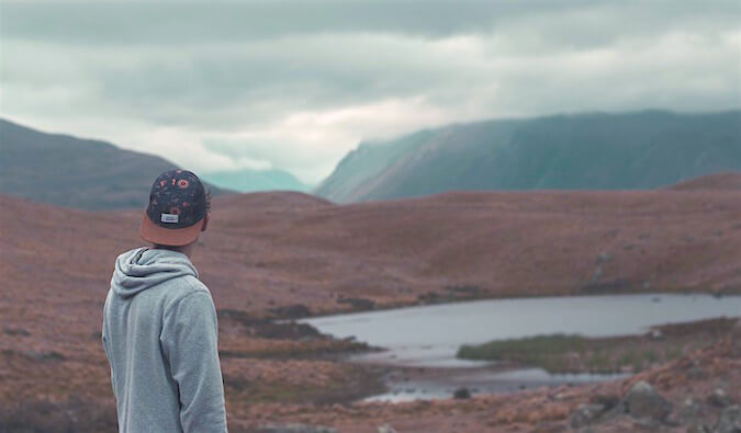 A guy in a sweater overlooking a lake and mountains