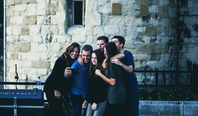 group of 6 friends huddled close together taking a selfy