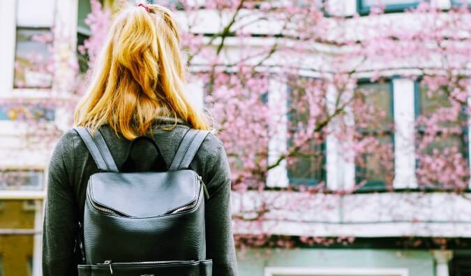 A woman with a backpack on stood outside a house preparing to go in