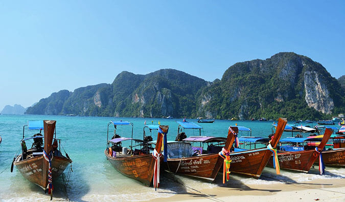 classic shot of Thai wooden long boats tied up on a Thai beach