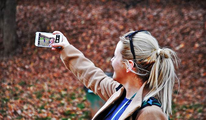 woman in the woods taking a selfy with her smart phone