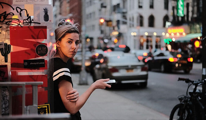 woman looking unhappy holding a smartphone on a busy city street