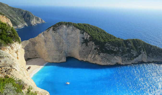 bright blue sea with a beach surrounded by high cliffs taken from above