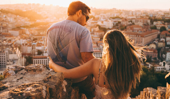 man and woman looking down over a city during the golden hour before sunset