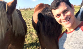 Matt Kepnes, aka Nomadic Matt, hanging out with Icelandic horses in a field in Iceland