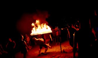Tourists playing limbo under a fire stick