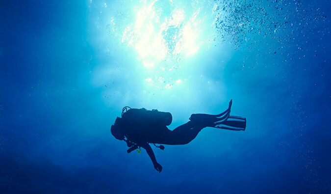 Alex scuba diving in blue water with sunlight shining through