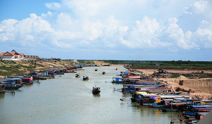 a lake in Cambodia with boats lining each side and some traveling down the lake