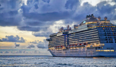 A large cruise ship sailing into the cloudy sunset