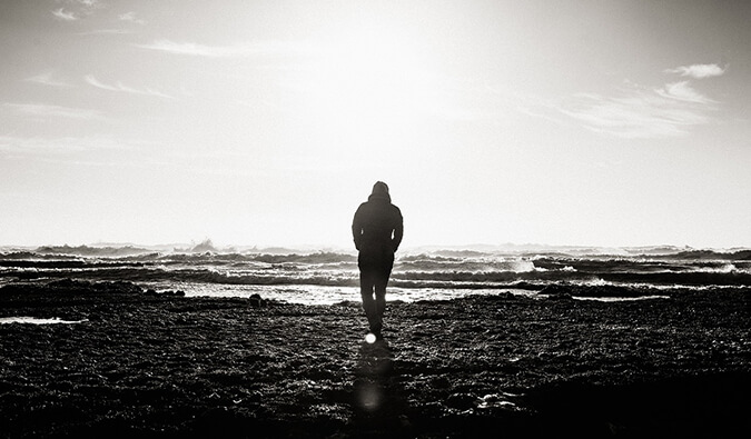 man walking along the beach alone in black and white