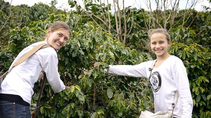 a woman and a girl smiling and picking fruit volunteering abroad