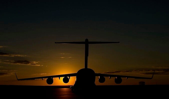 A big jet flying into an orange sunset