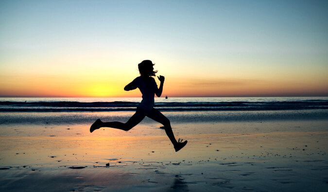 silhouette of woman running along the beach