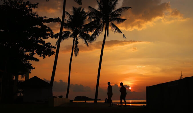 sunset silhouette image of two people walking on a beach in Koh Lanta Thailand