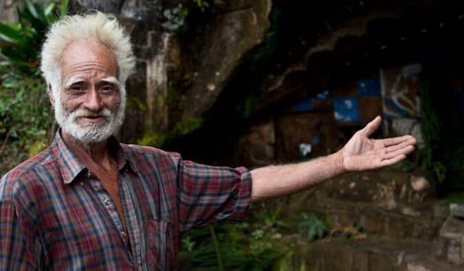 older Nicaraguan stone carver gesturing towards his work