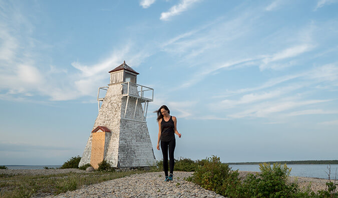 Kirstin walking towards the camera with a lighthouse in the background