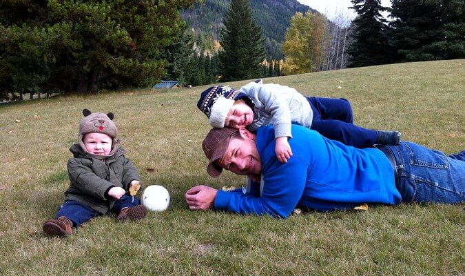 father and sons playing on the grass during their road trip