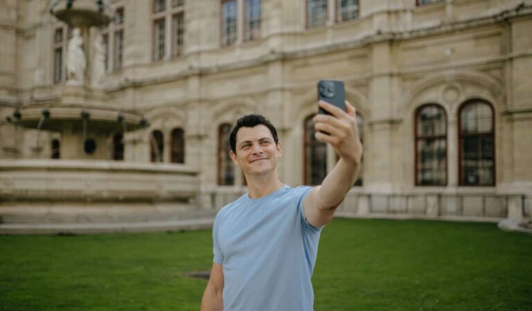 Nomadic Matt taking a selfie in front of a historic building and fountain