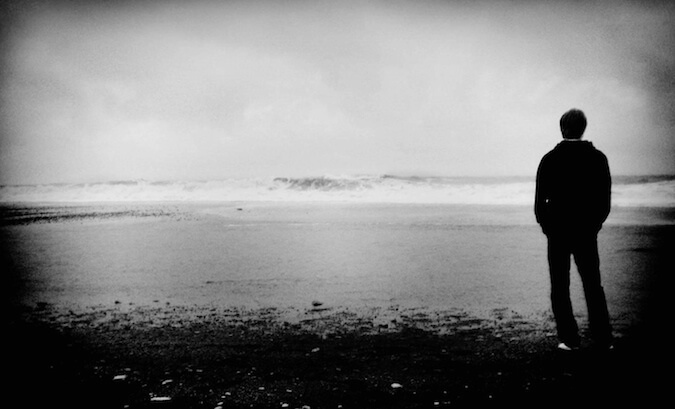 Black and white photo of a guy overlooking a lake