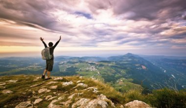 A solo traveler standing on a mountain looking into the distance