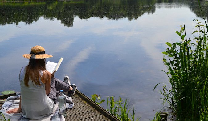 A woman reading a book on a lake