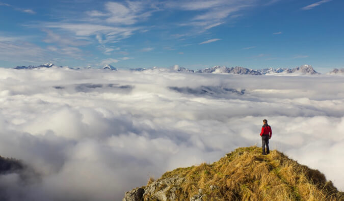 A man standing on the top of the mountains overlooking clouds