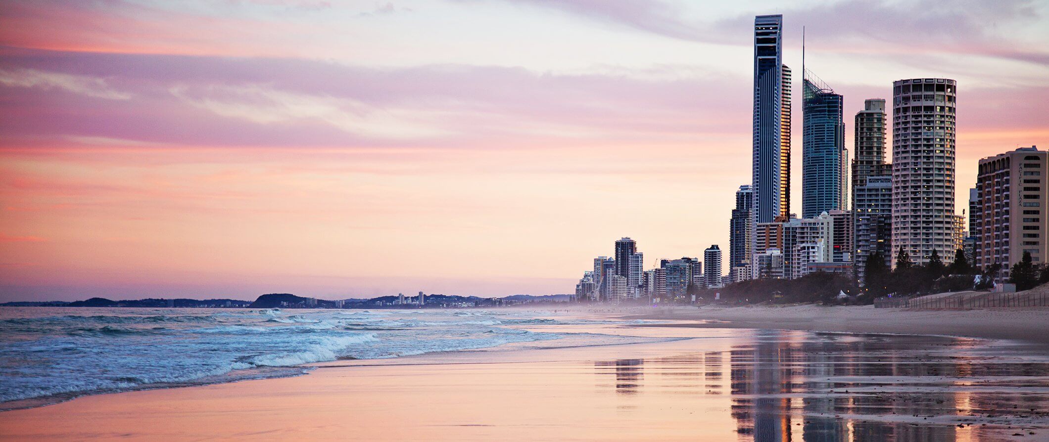 City meets the beach in Australia. Pink sky. Skyscrapers overlooking the beach at sunset