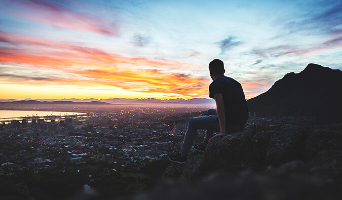 Nomadic Matt sitting looking out over a city at dusk