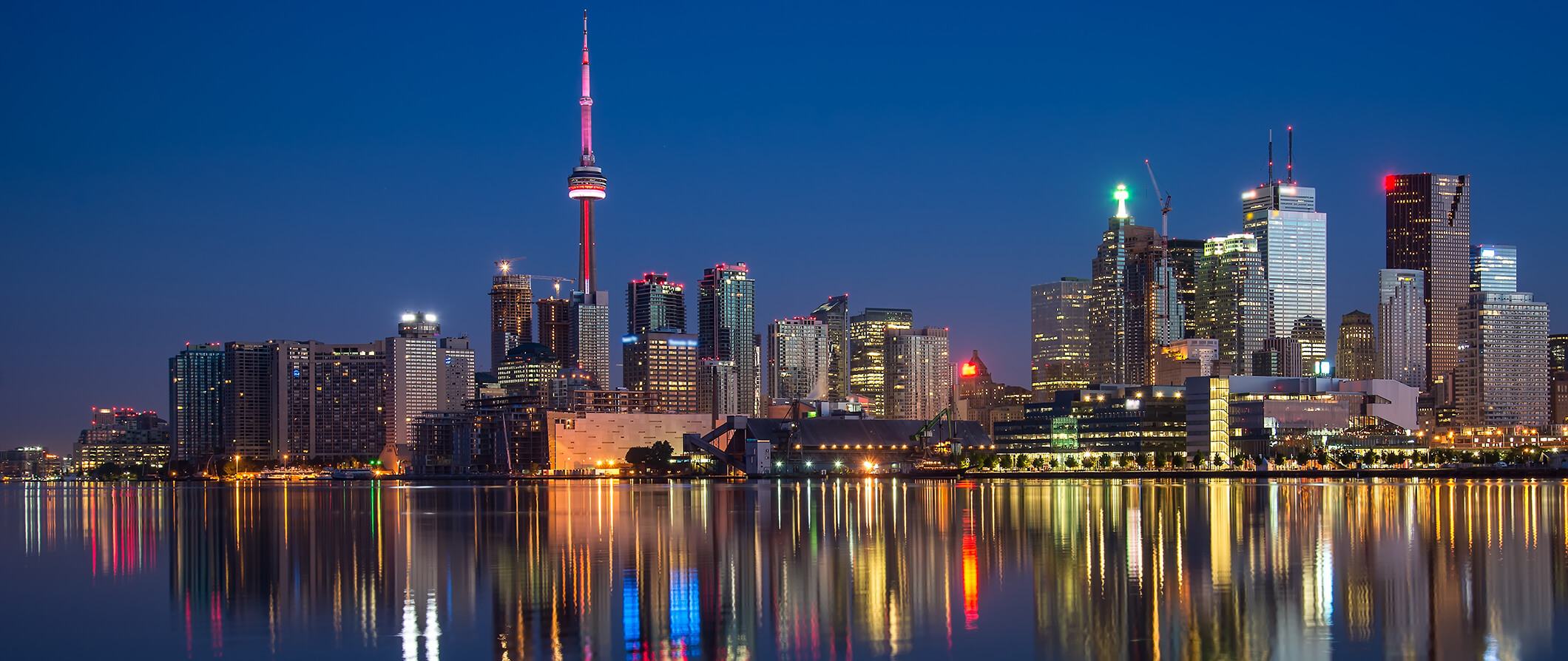 view of Toronto lit up at night with lights reflecting in the water