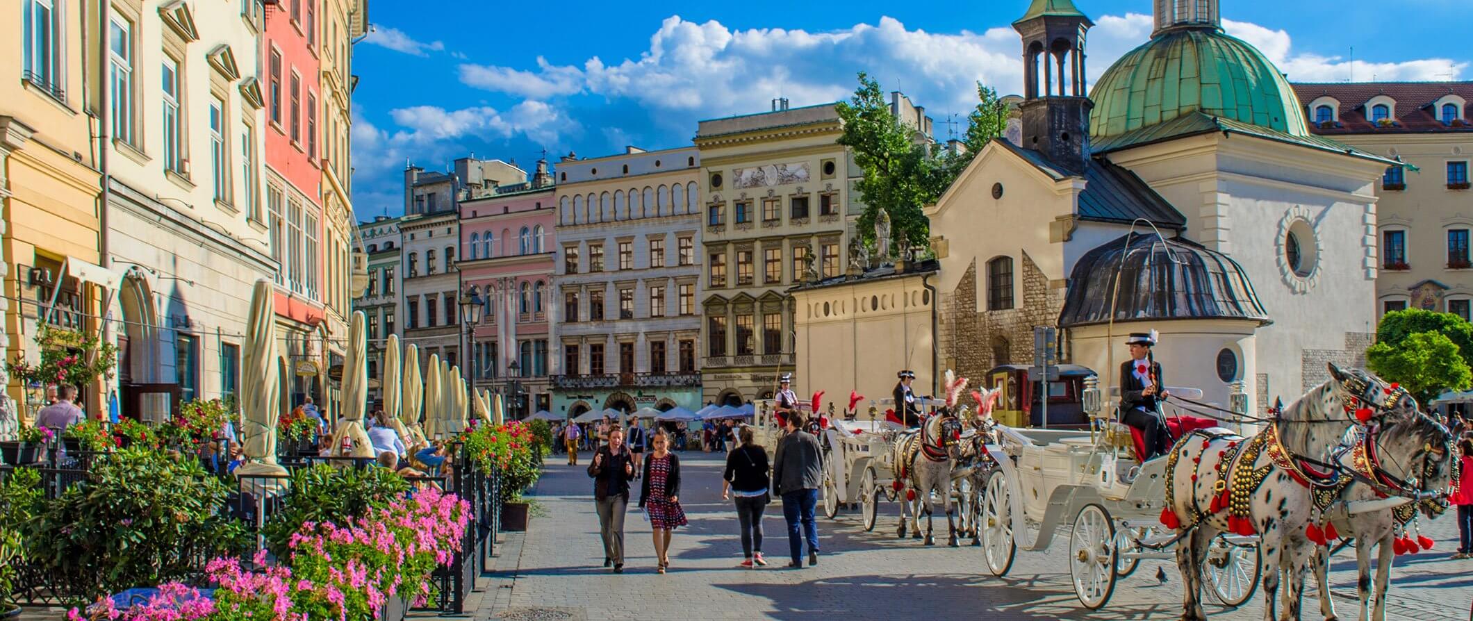 city view of Krakow in Poland. People walking the street and horse and carts lines up waiting.