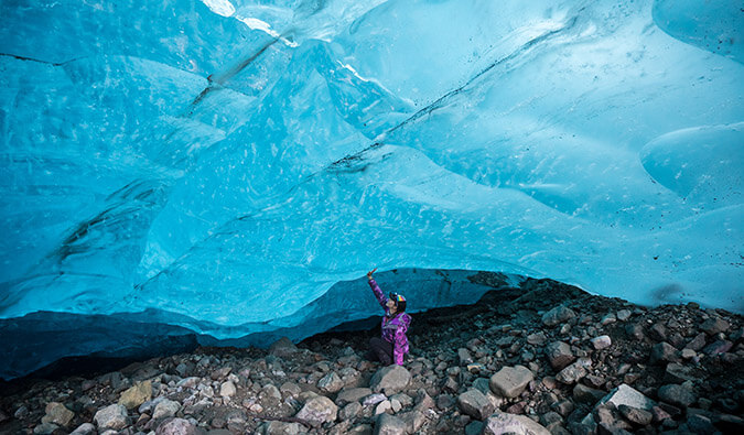 solo female reaching up to touch a ceiling of ice