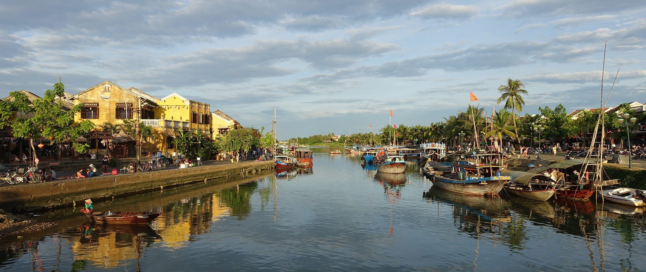 Hoi An river with fishing boats to the right and houses to the left