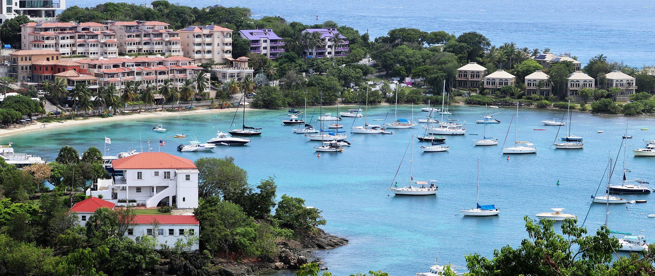 St John in the Caribbean. Sea, boats, and beach - with houses in the background.