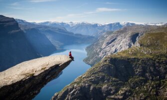 Person sitting on Trolltunga Rock above a fjord in Norway