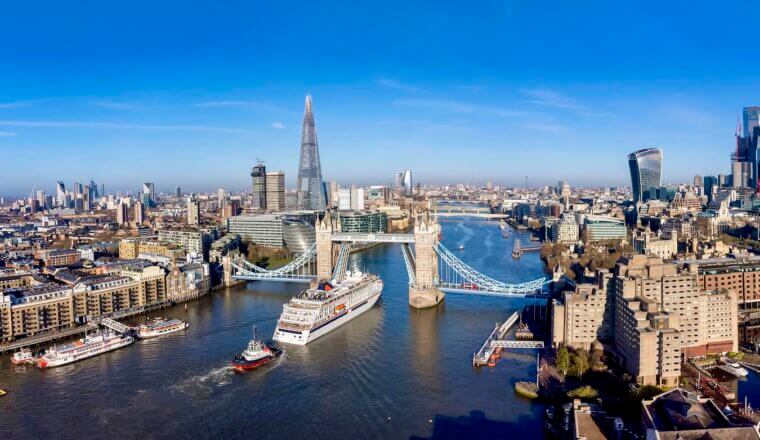 he iconic London skyline over the Thames with boats cruising up the river