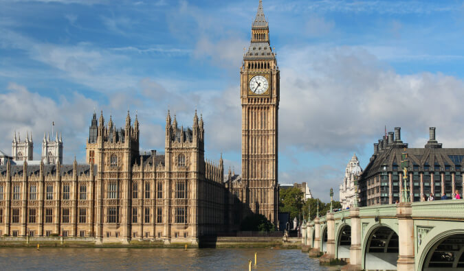 london looking across The River Thames with the houses of parliament and big ben to the left