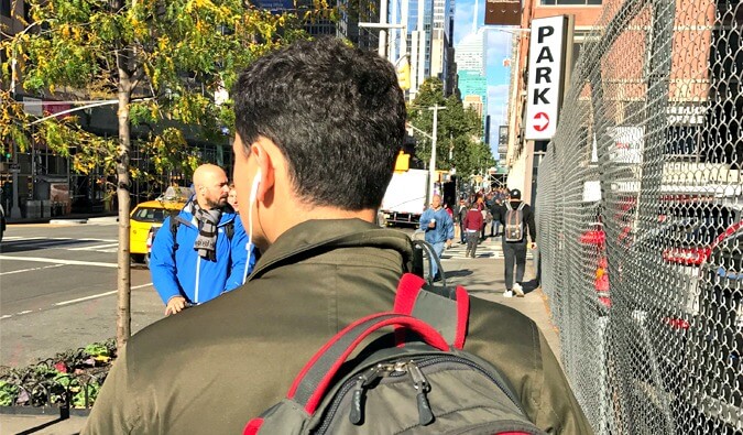 Nomadic Matt walking down a New York City Street backpack on and earphones in ears