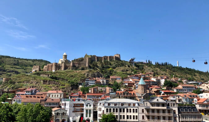 buildings built on a hill blue sky and a cable cart to the right of the image