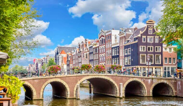 the canals of Amsterdam on a sunny summer day with row houses in the background