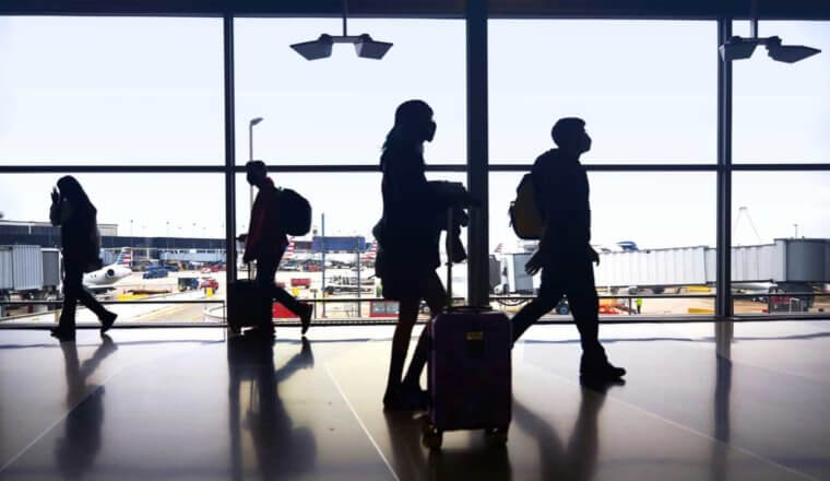 people silhouetted by a window at an airport