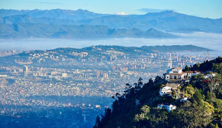 The towering skyline of Bogota, Colombia as seen from a scenic view over the green hills nearby
