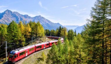 A red train going through the Swiss mountains