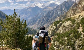 A lone backpacker sitting on a cliff looking at the mountains