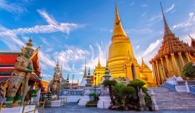 golden spires of temples in Bangkok set against a bright blue sky