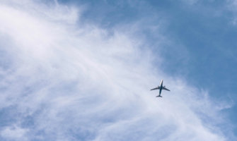 A lone airplane flying through a bright blue sky