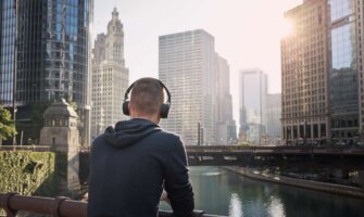 man wearing a pair of over ear headphones while looking out over the skyline of chicago