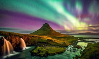 The northern lights in Iceland at night over a lone mountain in the snwoy landscape