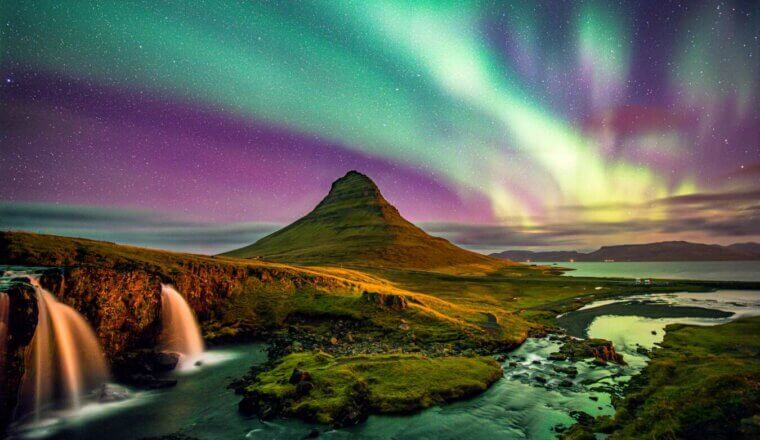 The northern lights in Iceland at night over a lone mountain in the snwoy landscape