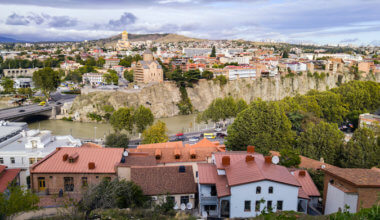 a view of Tbilisi from one side of the river bank, with homes and a church at the bank's edge