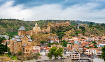 Tbilisi Old Town with historic buildings, churches, and city walls set into the rolling hills behind